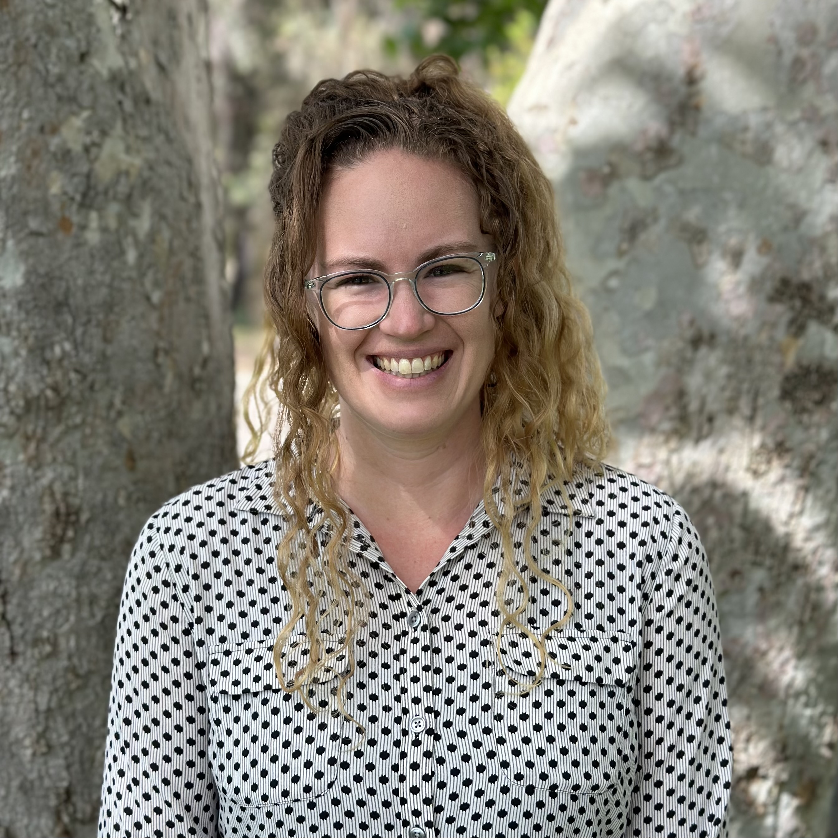 A blonde girl with curly hair in a polka dot shirt